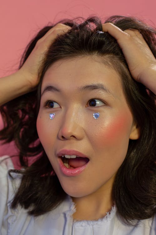 Asian female with rhinestones in shape of hearts on cheeks