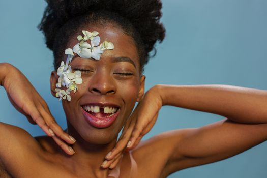 Joyful young ethnic lady smiling with closed eyes in blue studio