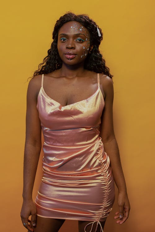 Alluring young black woman in trendy outfit looking at camera against yellow background
