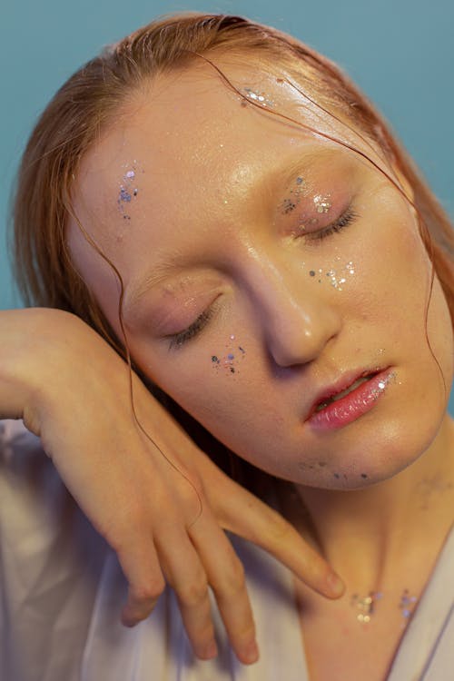 Sensitive woman with shiny glitters on face