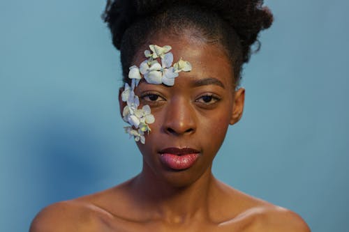 Attractive topless black woman with flower petals on face