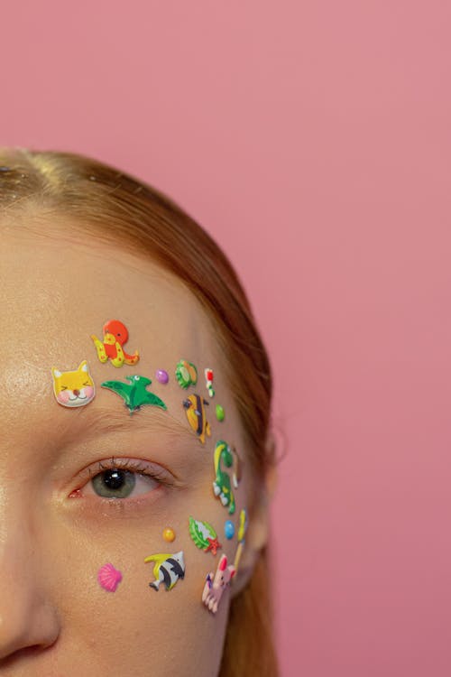 Crop redhead woman with childish stickers on face