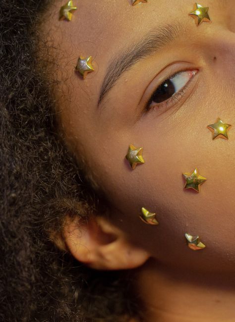 Crop attractive African American female with curly hair and golden stars on face looking at camera