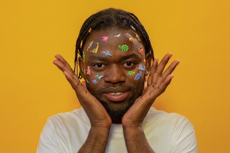 Positive Black Man With Colorful Stickers On Face In Studio