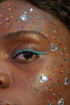 A captivating close-up of a woman's face with colorful glitter and rhinestones creating unique eye makeup.