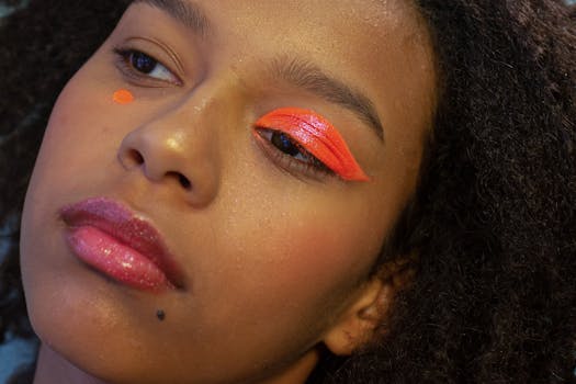 Crop young pensive black female model with bright creative makeup and dark Afro hair looking away in studio