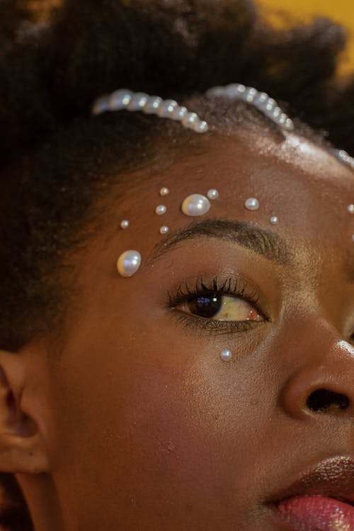 Stylish young black woman with pearl rhinestones on face looking at camera