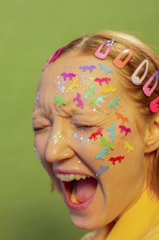 Young woman with childish stickers on face shouting in studio