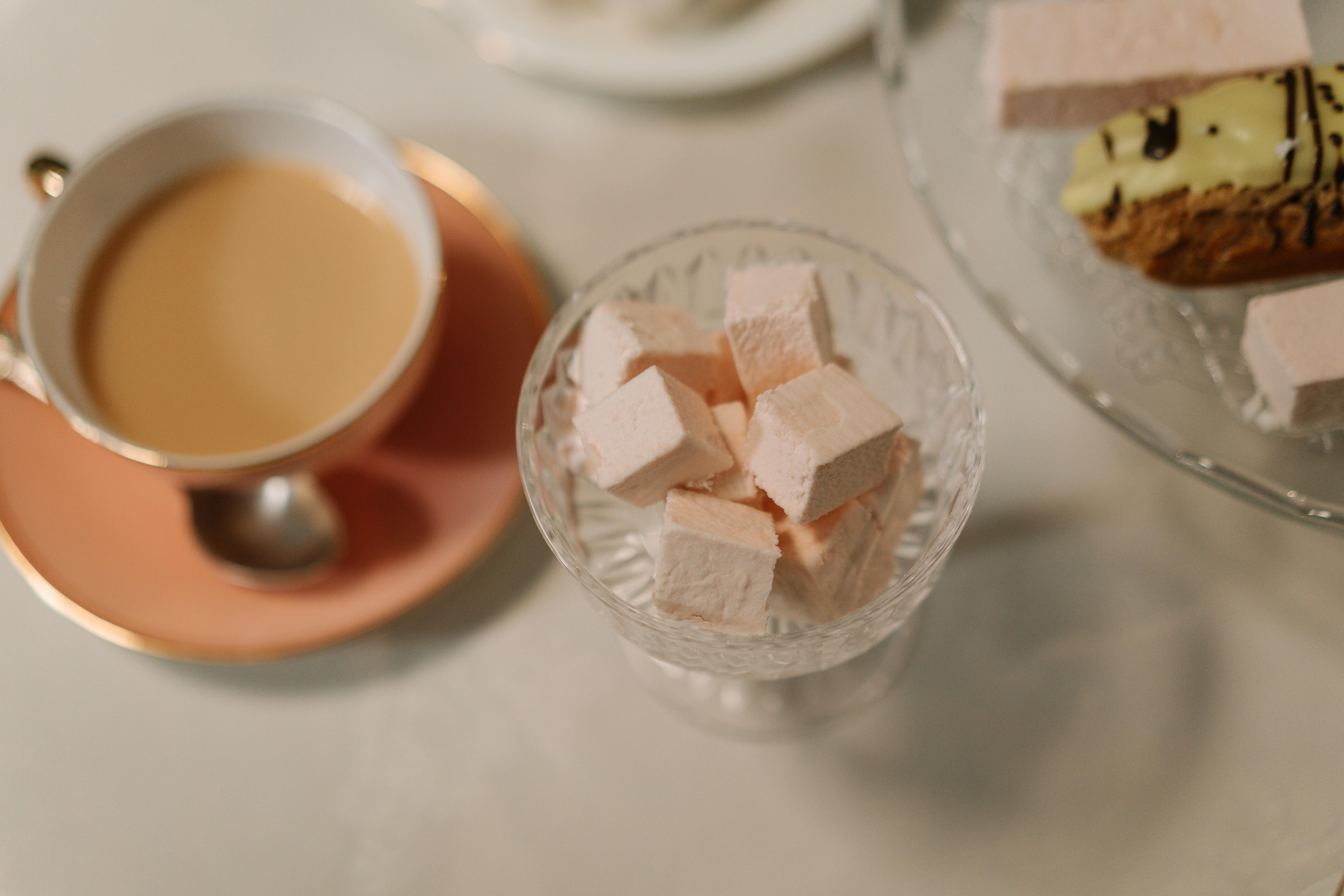 Inviting tea and dessert scene featuring pink marshmallows and a cup of tea on a pastel saucer.