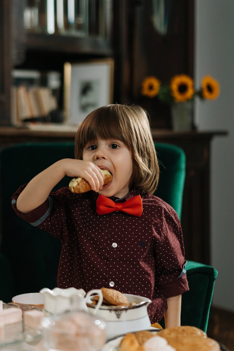 Close-Up Shot Of A Little Kid In Red Bow Tie Eating Food