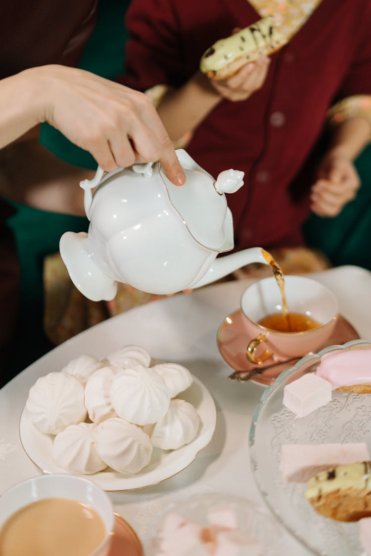 Hand Of A Person Pouring Tea From Pot To Cup