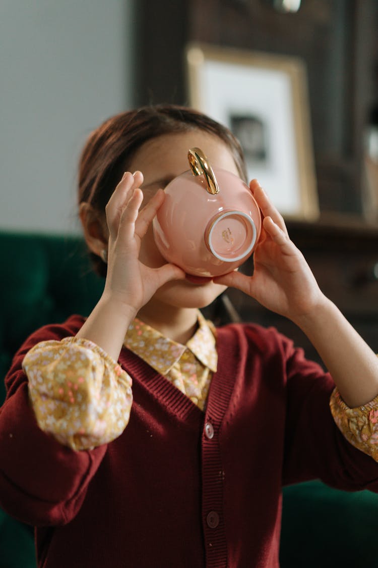 Girl Drinking From Cup Covering Face