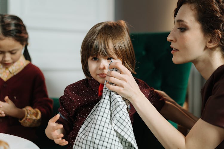 Woman Sitting To Wipe A Child's Face