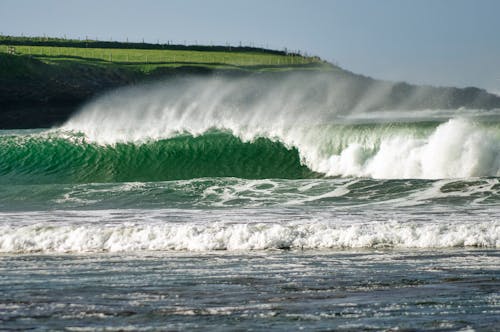 Free Crashing Waves Near a Green Grass Land Stock Photo