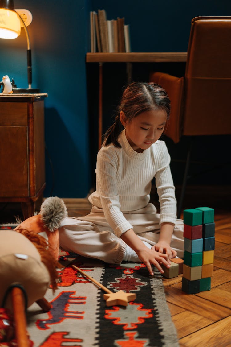 A Girl Arranging Wooden Toy Blocks On The Floor