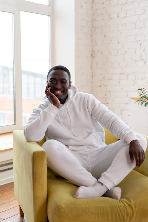 Free Positive black man relaxing in yellow cozy armchair Stock Photo