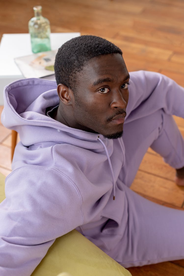 Serious Black Man Sitting On Floor Near Couch