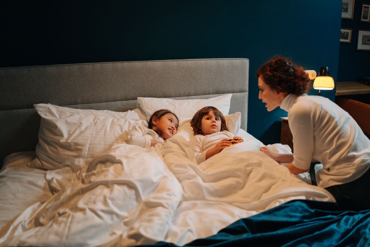 Une adulte lit une histoire à deux enfants avant le coucher