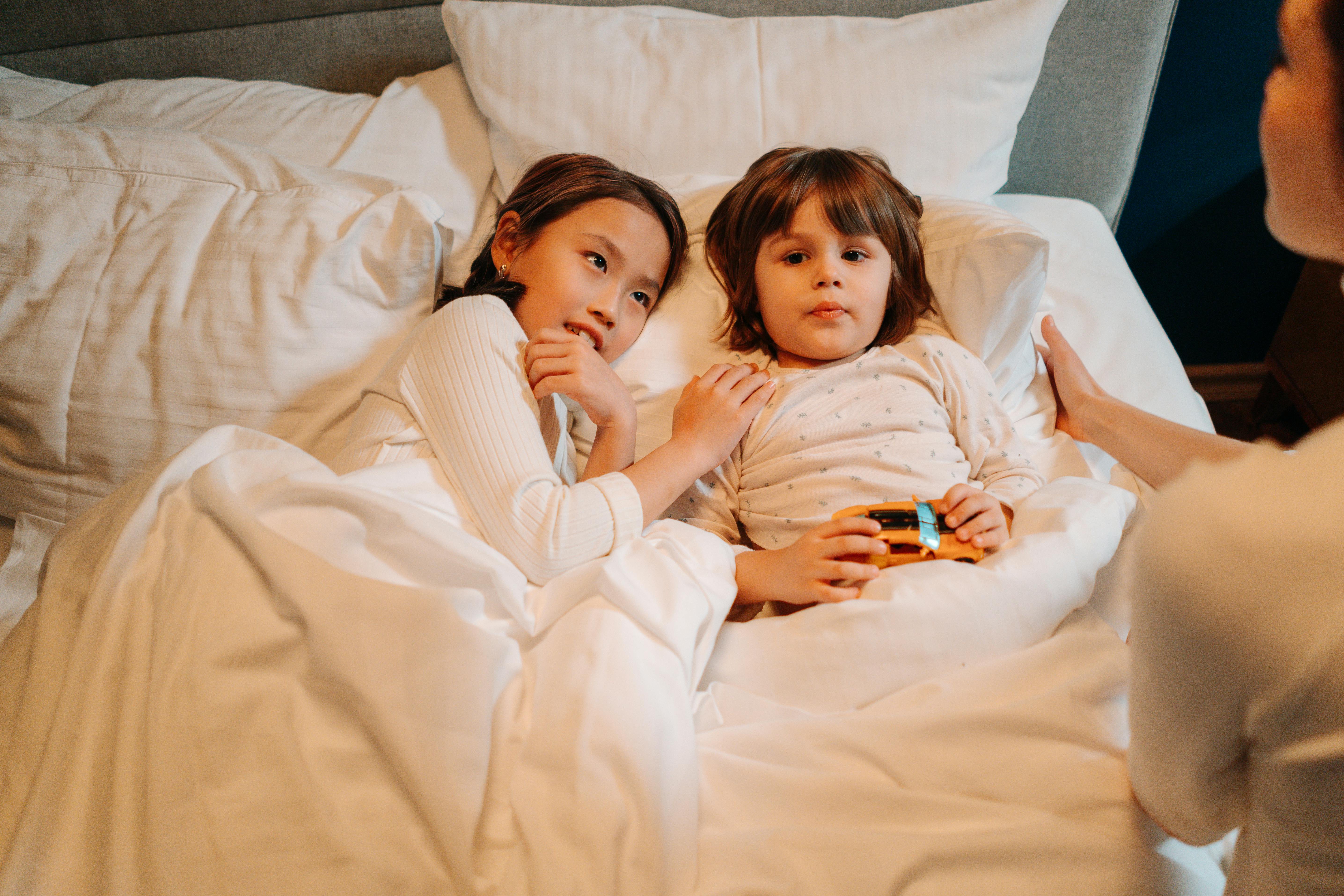 children listening to a woman sitting on the edge of the bed