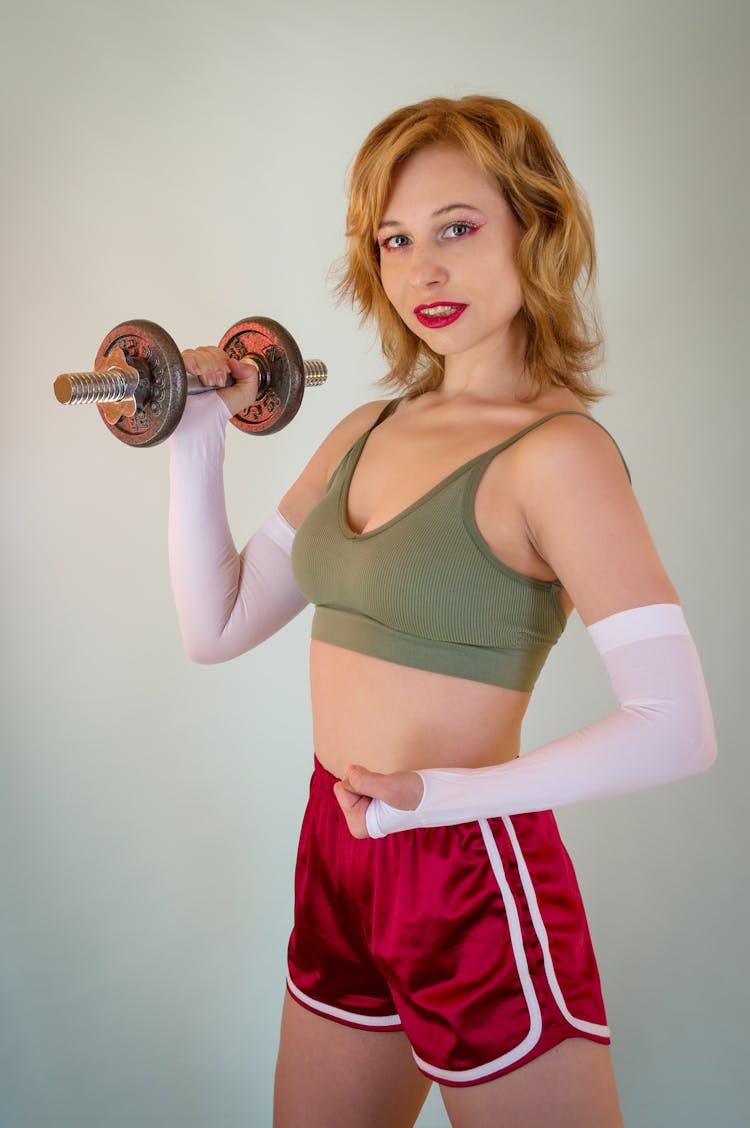 Fit Sportswoman With Dumbbell During Training On Light Background