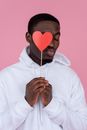 Black man making kiss gesture with paper heart prop