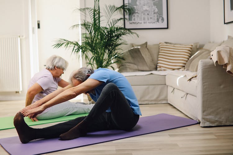 A Couple Sitting On Yoga Mats Stretching Forward