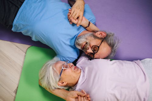 Couple Holding Hands with Eyes Closed Relaxing on Yoga Mats