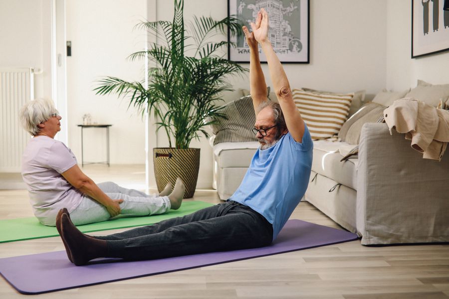 Older couple staying active together on exercise mats at home