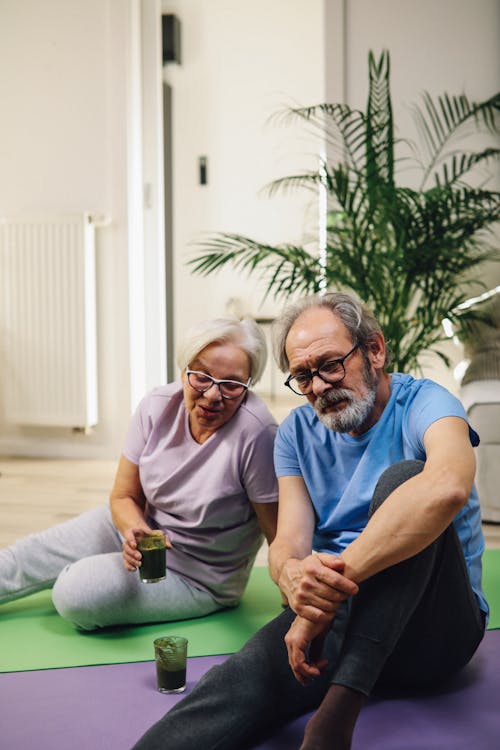 An Elderly Couple Talking While Sitting on Yoga Mats