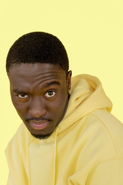 A Man in Yellow Hoodie Looking with a Serious Face