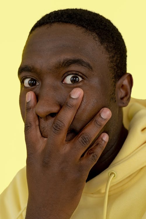 A Man in Yellow Sweater Covering His Mouth