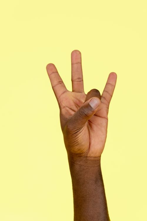 Free Close-up shot of a hand making a gesture against a vibrant yellow background. Stock Photo