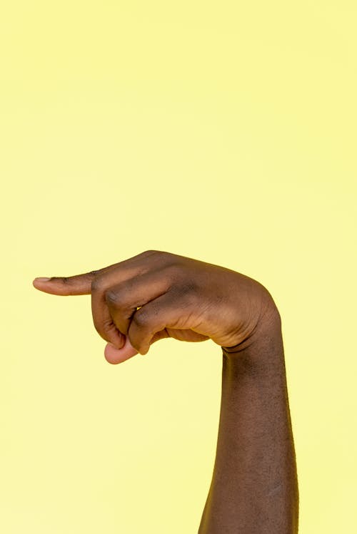 Hand Pointing a Finger on a Yellow Background