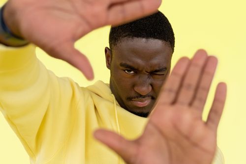 Free Close-up of an African American man making a framing gesture against a bright yellow background. Stock Photo