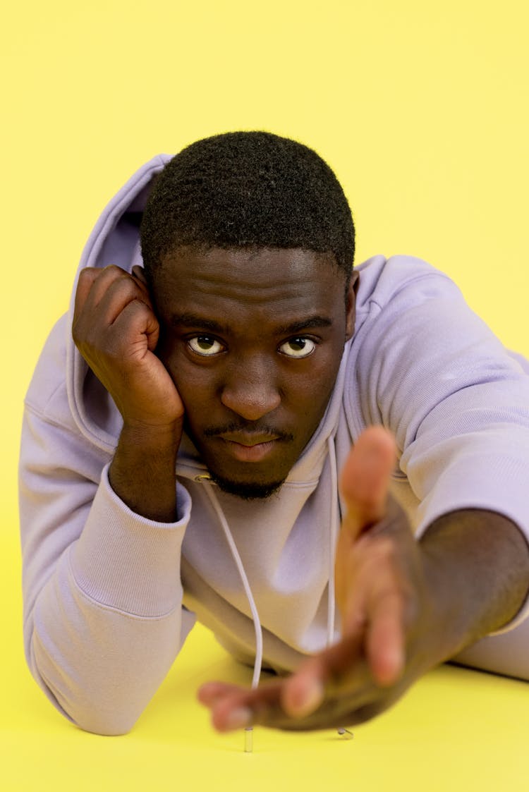 Man In Hooded Sweatshirt Lying On Front With Outstretched Arm