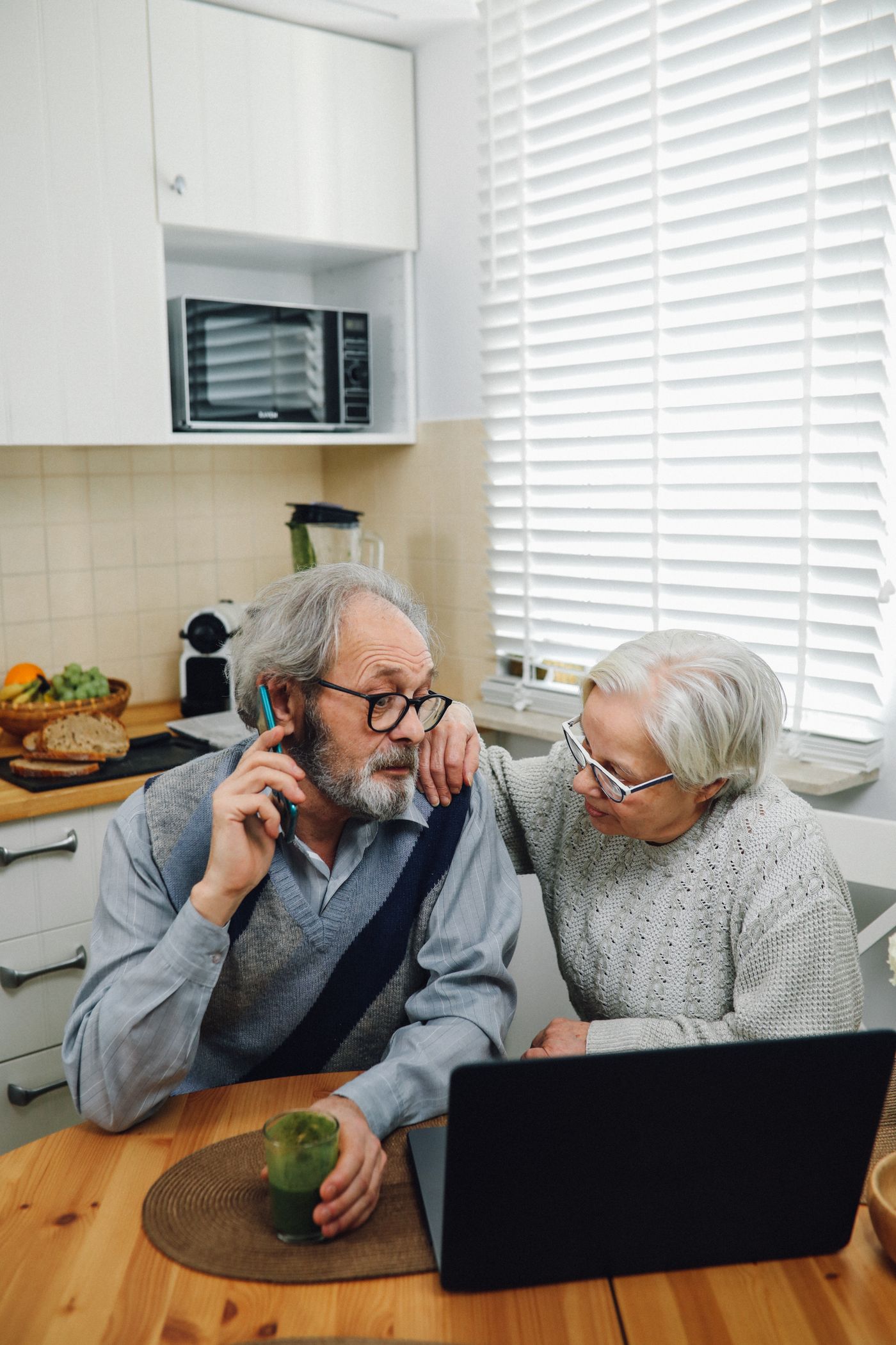 A couple checking information on a phone and laptop at home