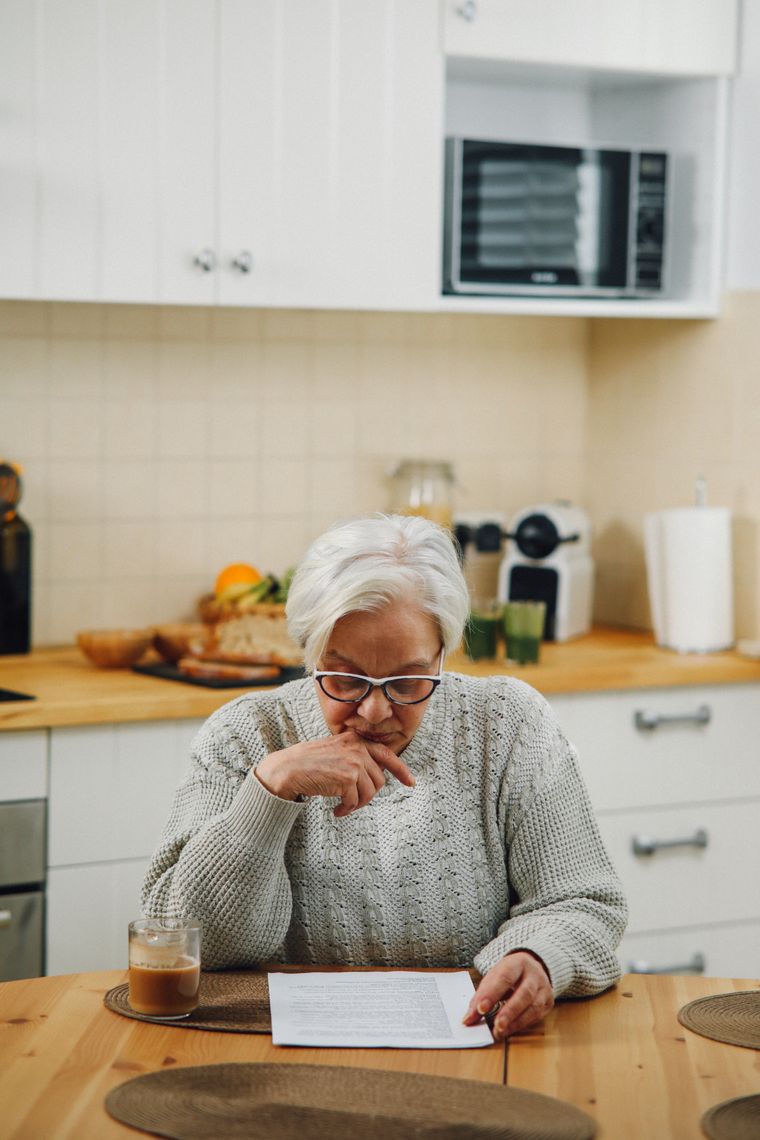 A woman reading a document at her kitchen table