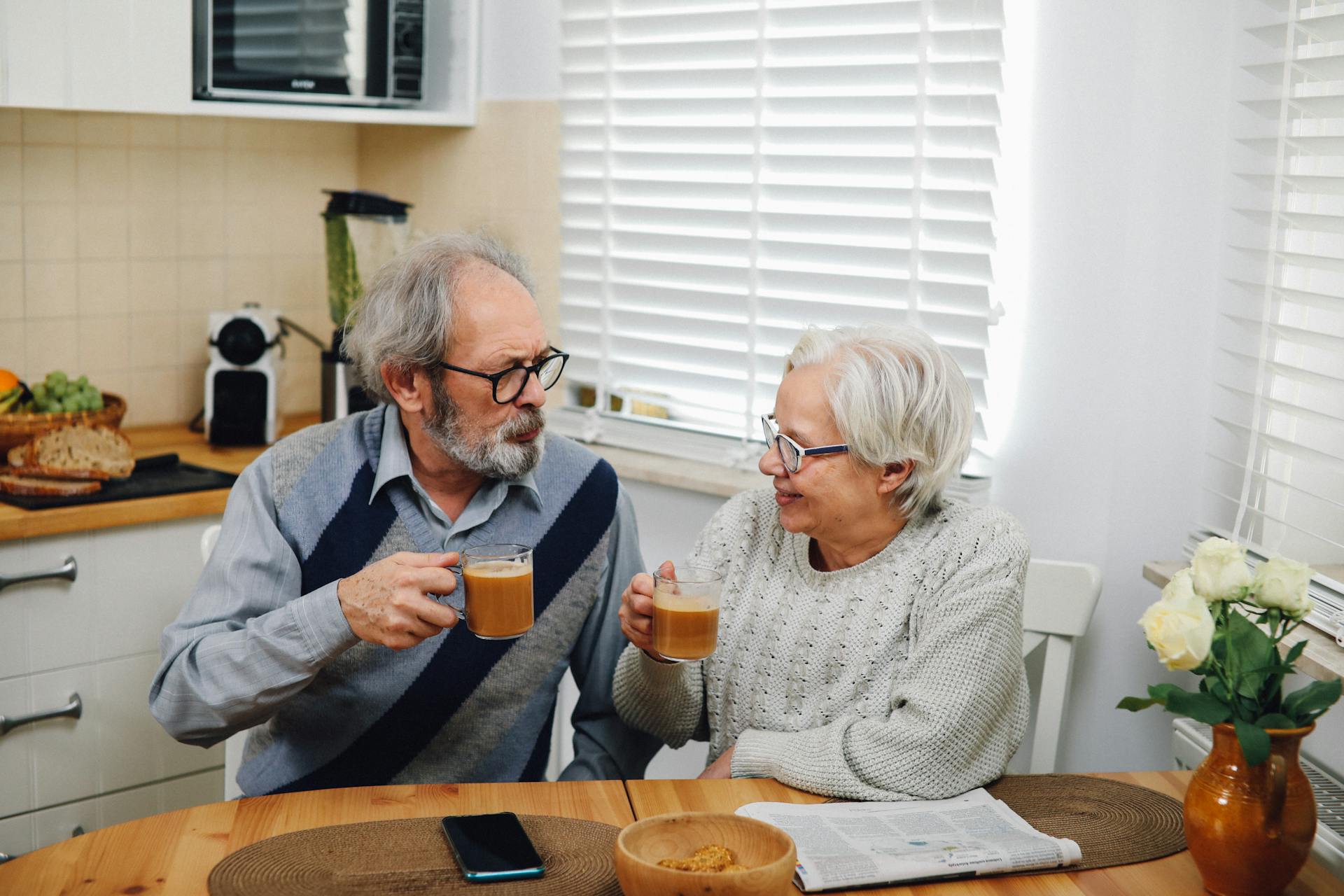 Senior couple enjoying coffee together at home in cozy kitchen setting.