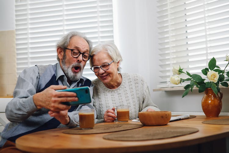 An Elderly Couple Looking At A Smart Phone