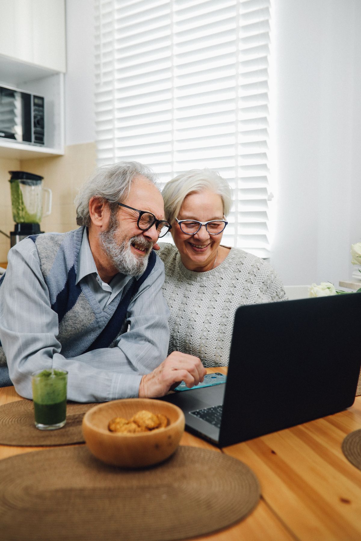 Senior couple smiling while learning about Medicare on a laptop