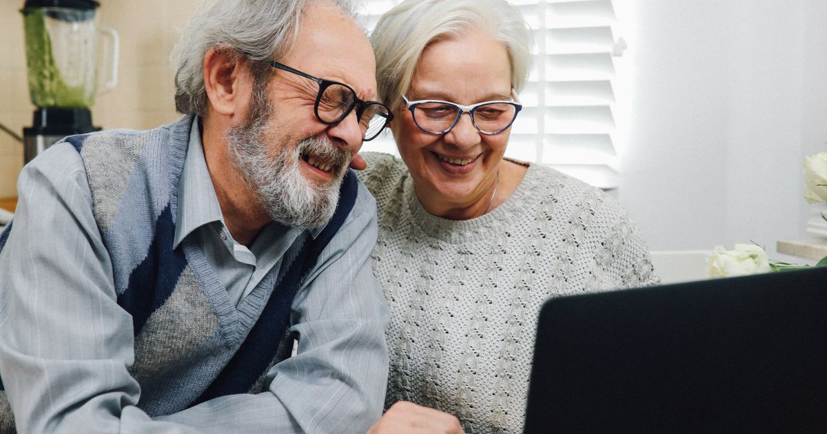 Senior couple smiling and using a laptop Social Security benefits
