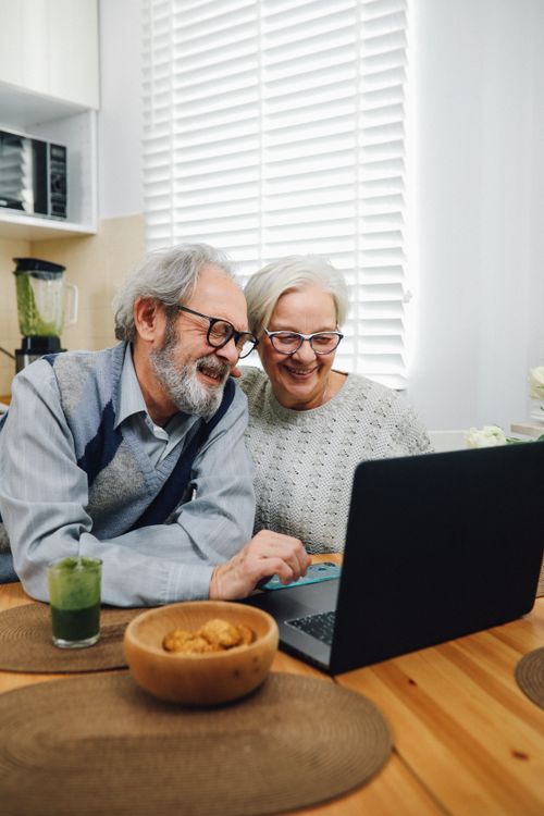Free Elderly couple happily using a laptop together indoors, smiling and engaged. Stock Photo