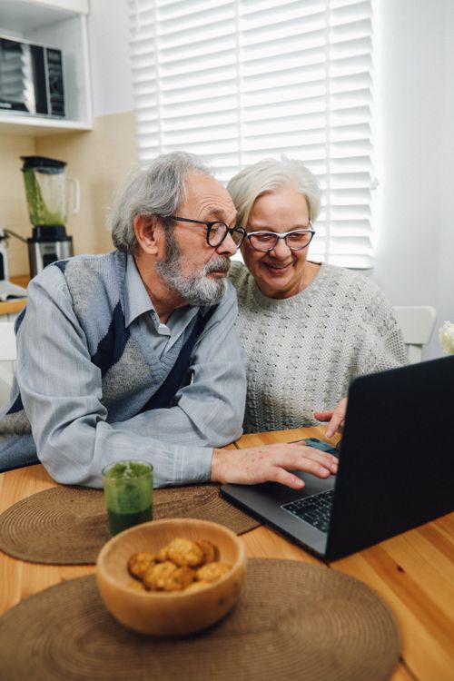 Free Elderly couple enjoying time together on a laptop in their cozy home kitchen. Stock Photo