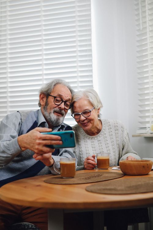 Free Happy senior couple taking a selfie indoors with coffee, capturing a warm and modern lifestyle moment. Stock Photo