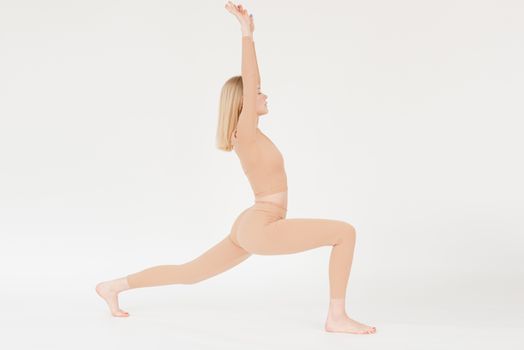 Woman in nude activewear performing a yoga pose, showcasing flexibility and grace.