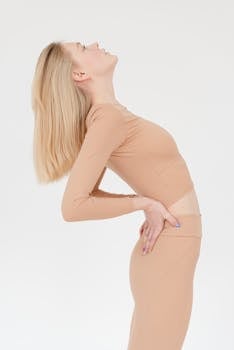 Woman in nude activewear performing a side stretch, emphasizing fitness and flexibility.