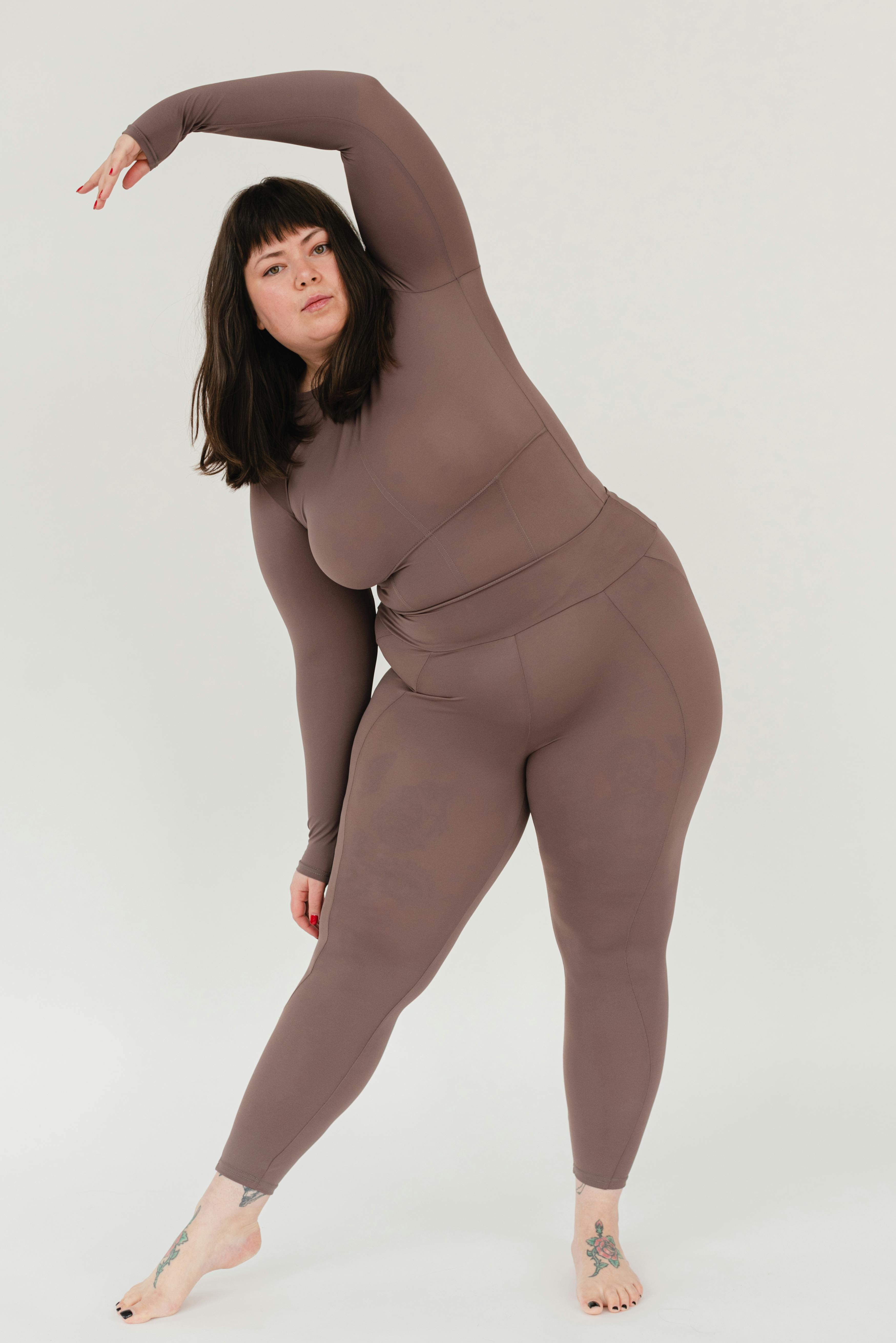 young plus size woman stretching body in white studio