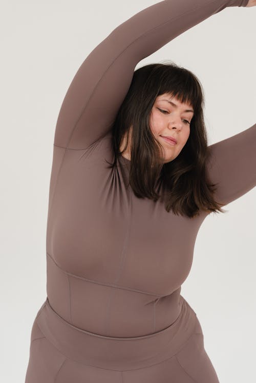 Free Young obese female doing bending exercise in white studio Stock Photo