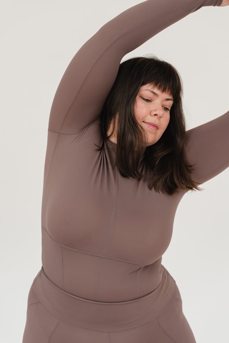 Young Obese Female Doing Bending Exercise In White Studio