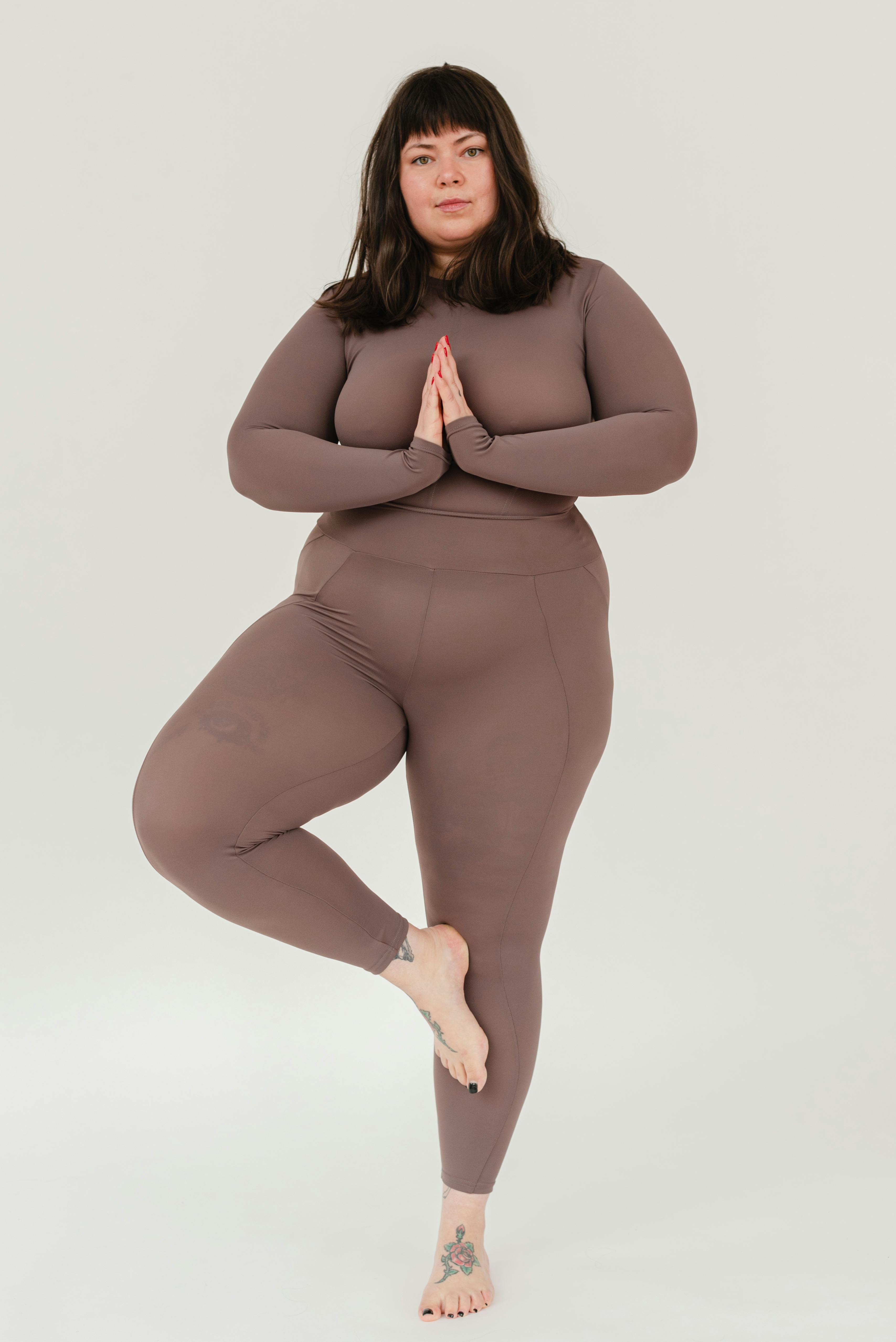 overweight young woman practicing tree asana during yoga lesson